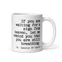 White mug with black text quote by St. Ignatius of Loyola on a white background