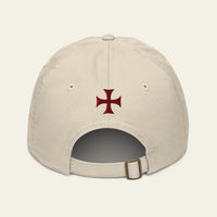 A light beige baseball cap shown from the back, featuring a dark red Iron Cross emblem embroidered in the center and an adjustable strap with a metal buckle at the bottom.