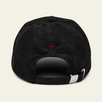 Black cap with a HERALDIC CROSS on the back against a BLACK background