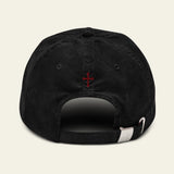Black cap with a HERALDIC CROSS on the back against a BLACK background