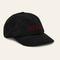 Black cap with red 'NIKA' logo on a beige background