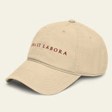 A beige baseball cap with 'ORA ET LABORA' embroidered in dark red on the front, shown against a solid light beige background.